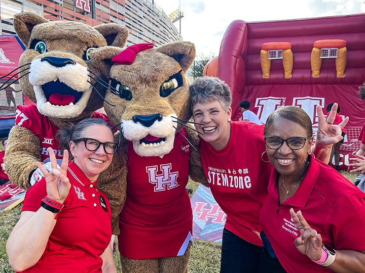 Two mascots and three women at a football game