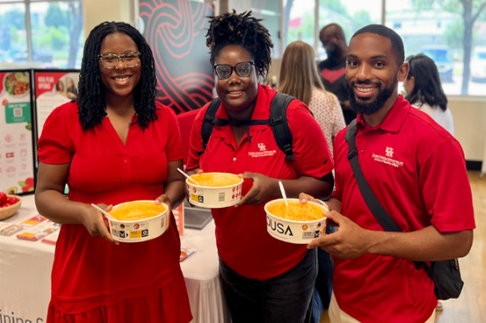 UH staff members holding bowls of ramen at the Cougar Village Market
