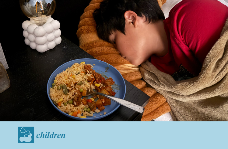An adolescent in bed with a plate of food on the table next to him