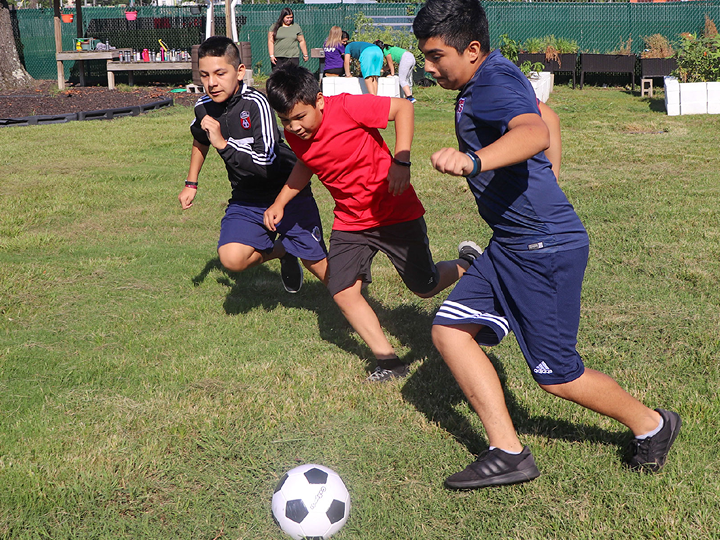 Three child playing soccer