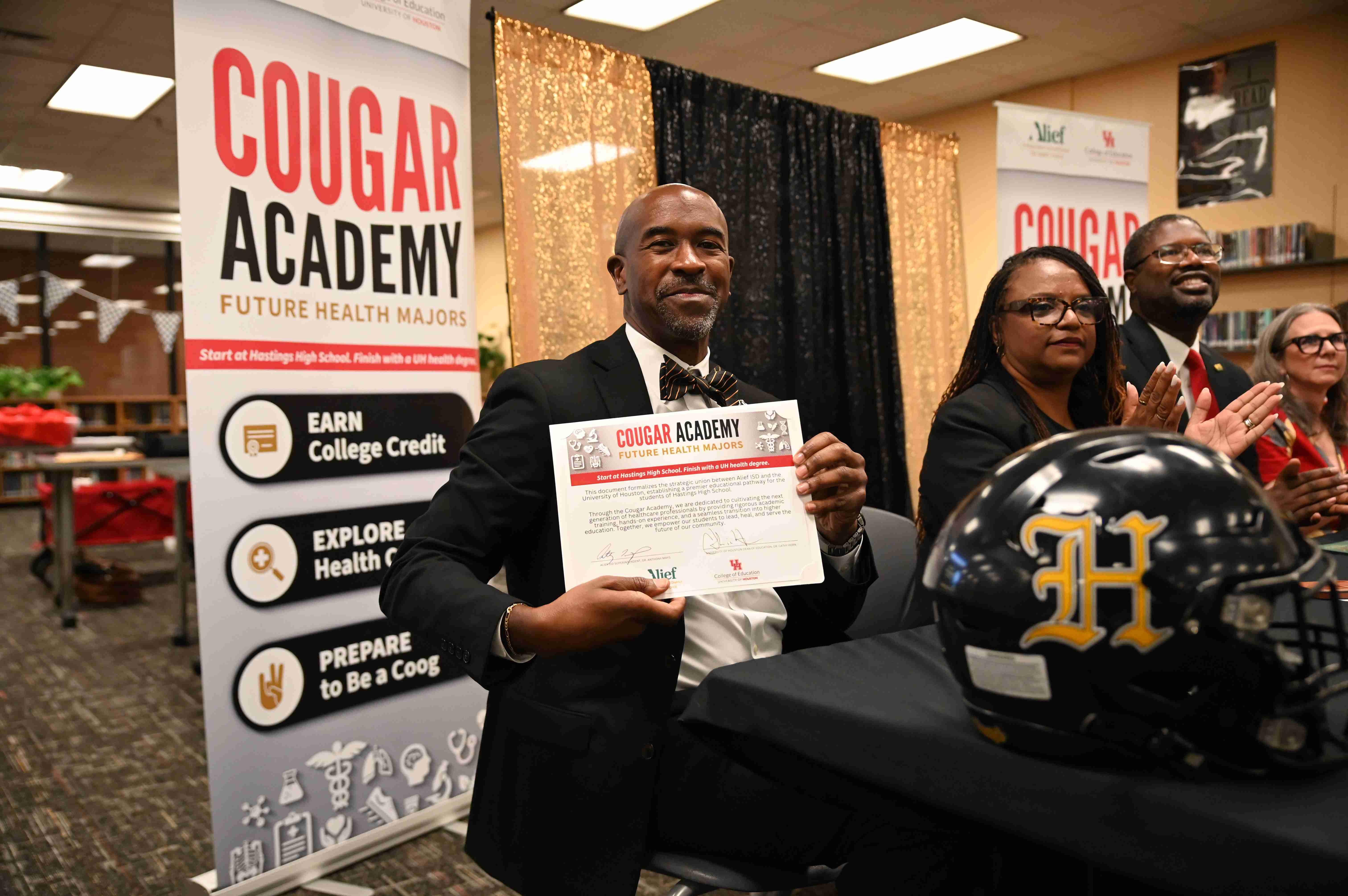 Man sitting with Cougar Academy sign