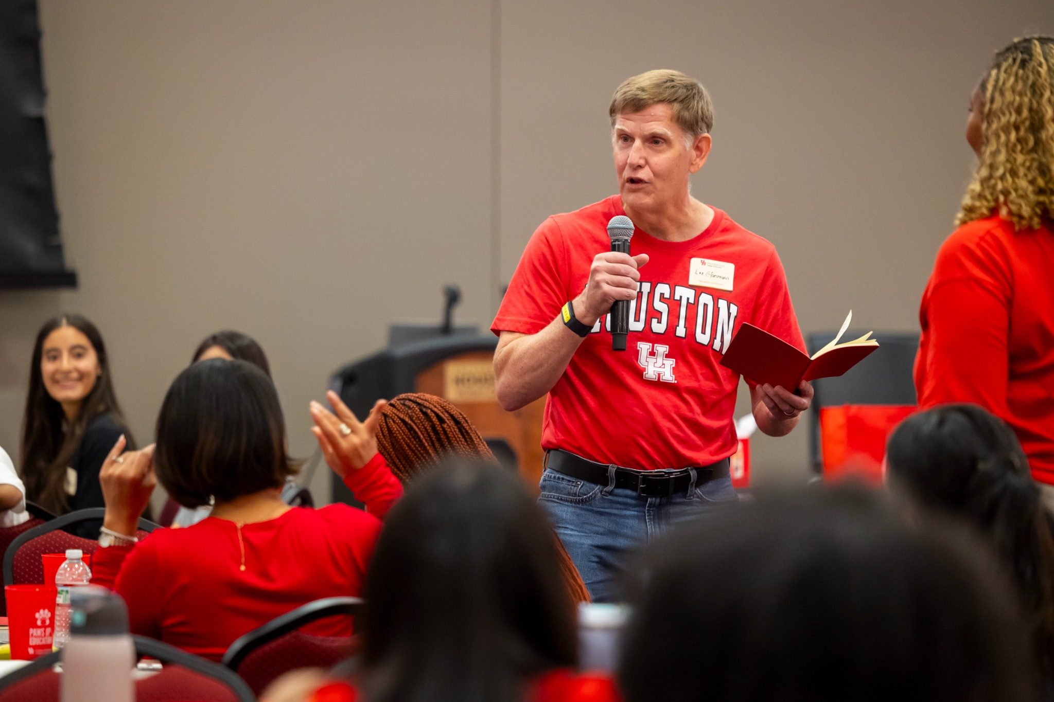 A graduate student stands and speaks into a microphone to his peers at Graduate Student Orientation.