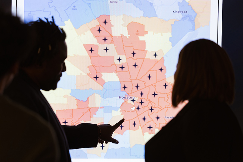 Two people looking at a map of Houston. They are in silhouette because of the lighting.