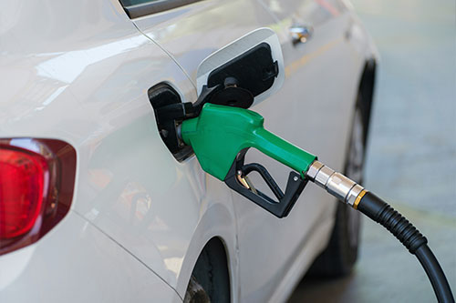 White sedan being refueled with a green gas pump nozzle