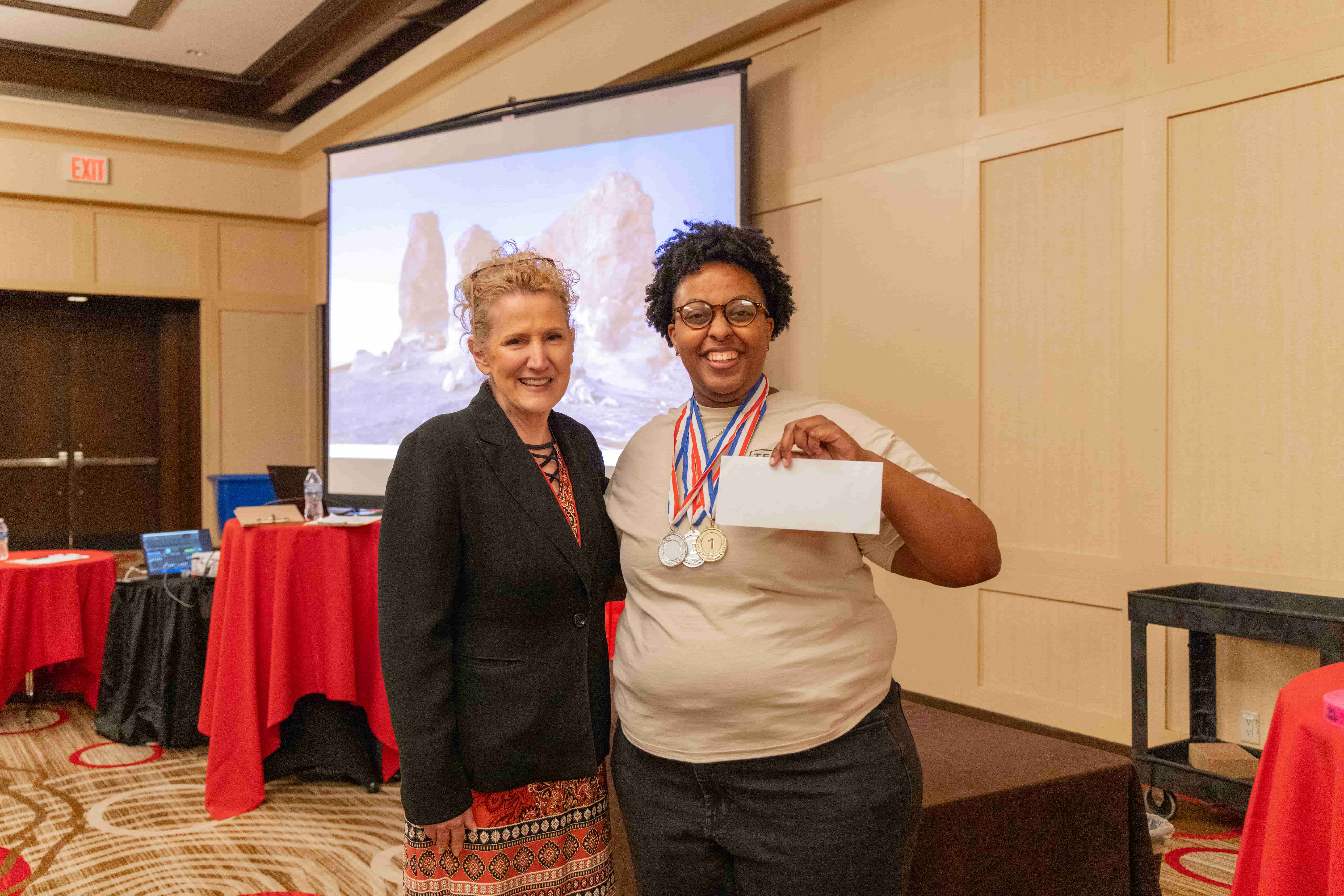 student posing for award with adult
