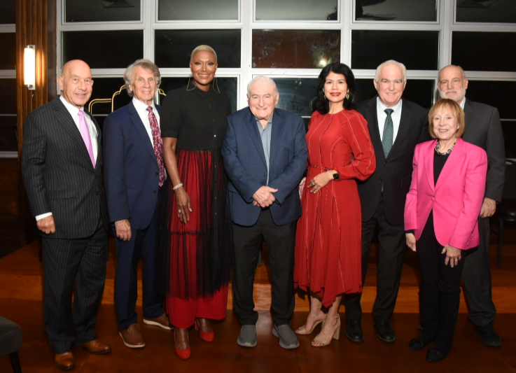 Group of people surrounding an older man in a blue sports jacket