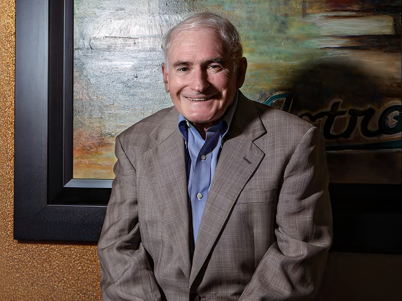 older white male in a grey sports jacket with a blue collared shirt