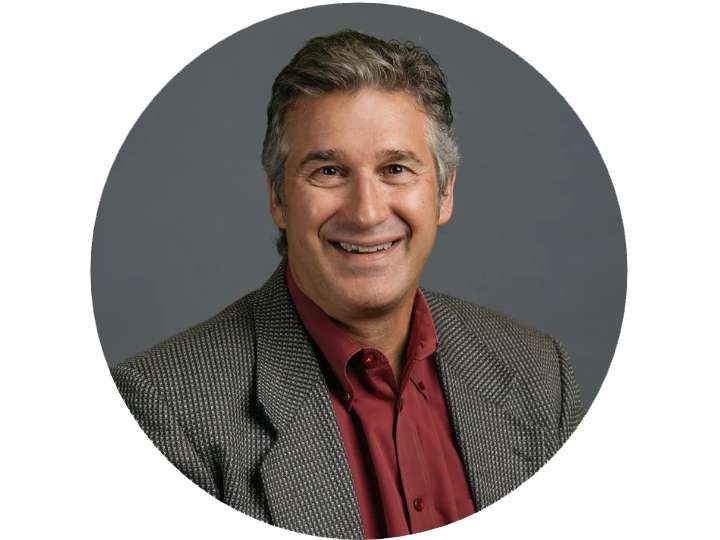 older white man with grey hair and a beige sports jacket with red shirt