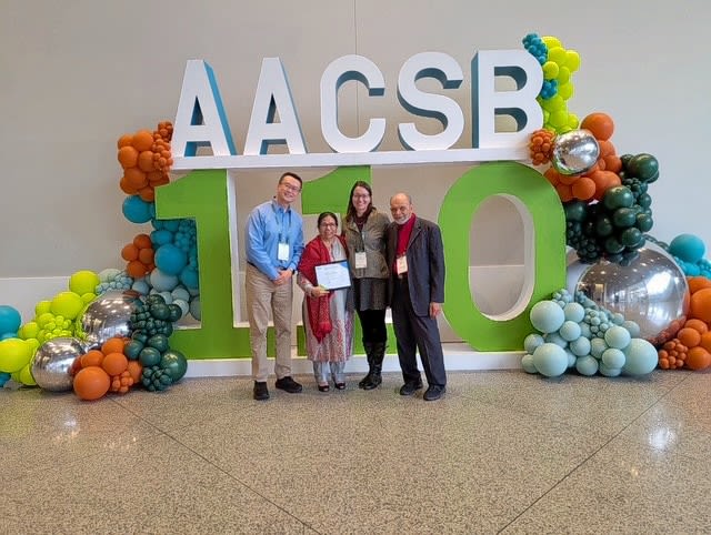 group photo in front of AACSB logo and balloons 