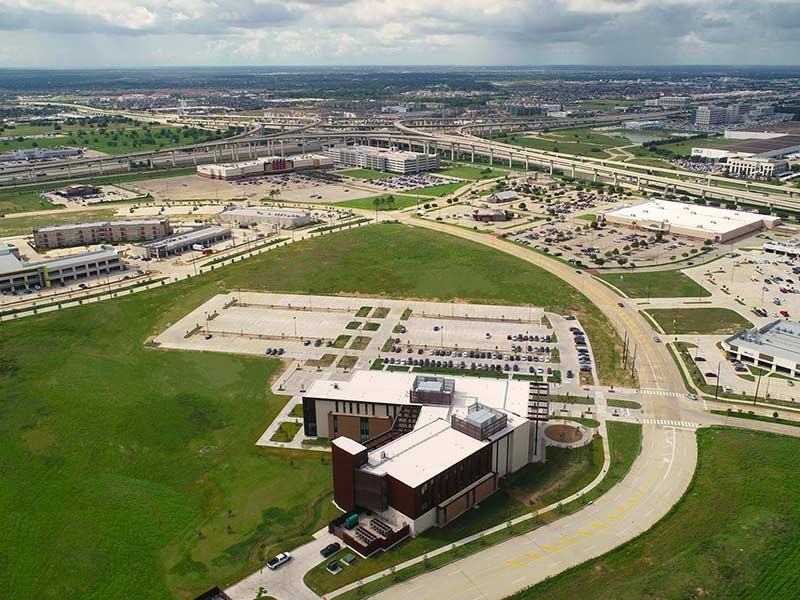 Aerial photograph showing the Katy Academic Building in the foreground and the I-10 and Highway 99 intersection in the background.