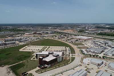 Aerial photograph of a small university campus with businesses and homes in the background.