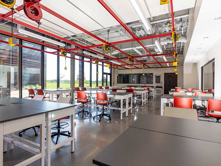 An engineering studio with power strips hanging from a grid on the ceiling over groups of tables.