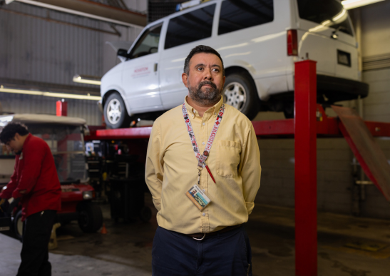 Image of Rocky Garcia standing in front of a truck that is lifted on a platform.