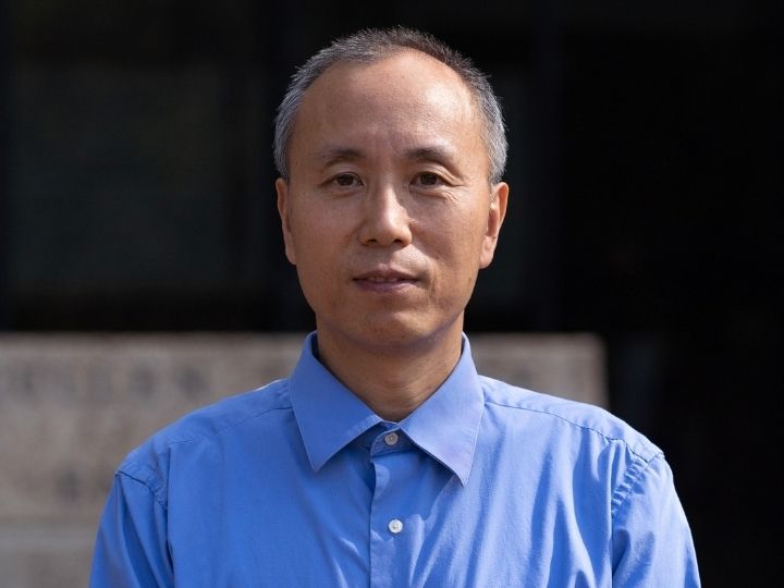 Professor of electrical and computer engineering Jiming Bao standing in a blue dress shirt.