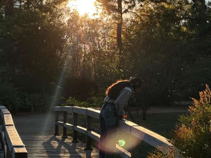 Person wearing brain cap peers over a bridge in natural park.