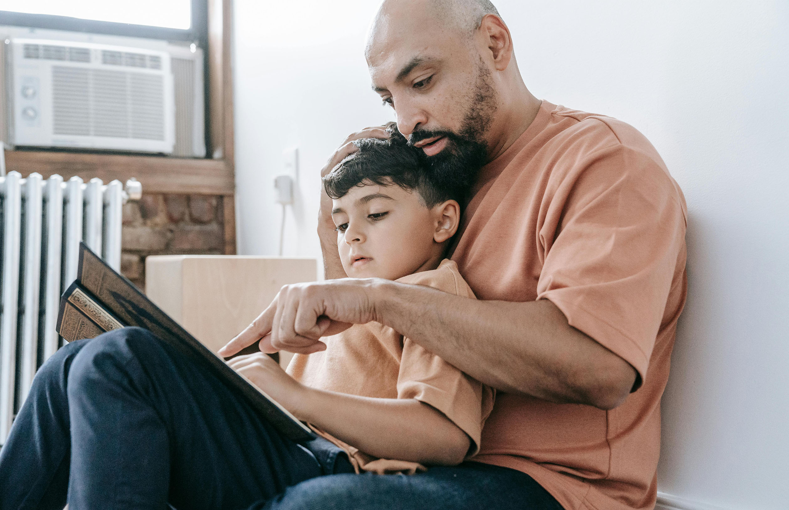 Father and young son sitting together to read