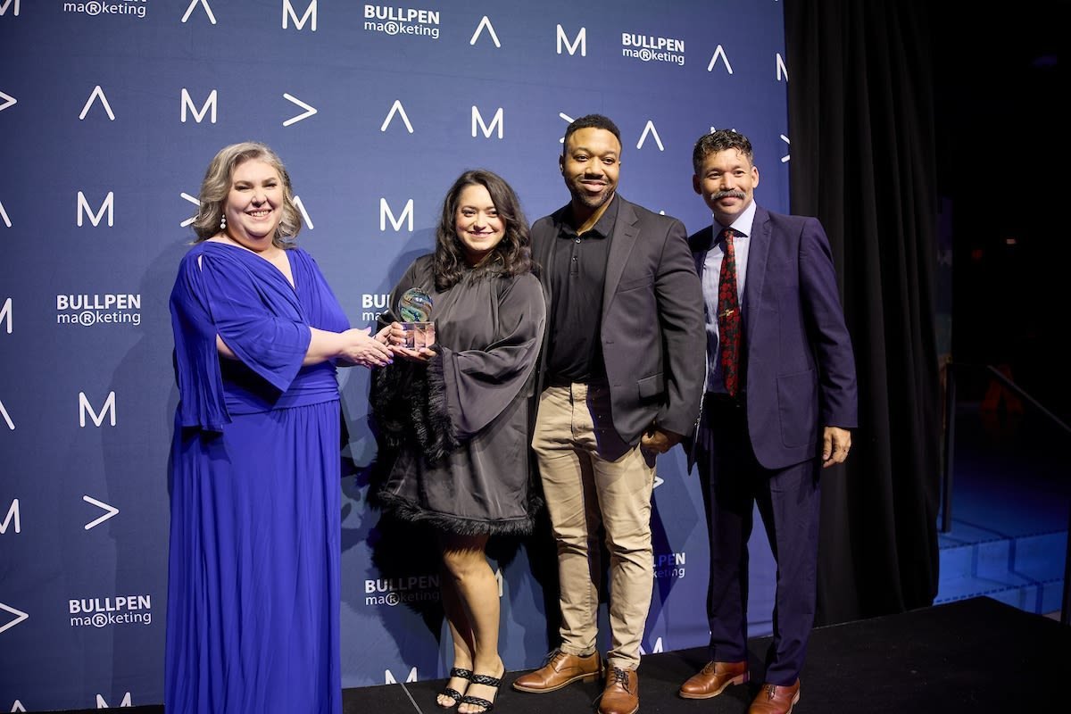 UH marketing and communication staff posing with their award in front of a blue backdrop.