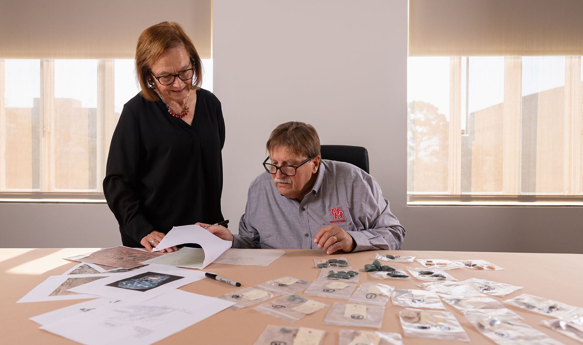 Diane and Arlen Chase looking at a table with many pieces of an ancient mask resting on it.