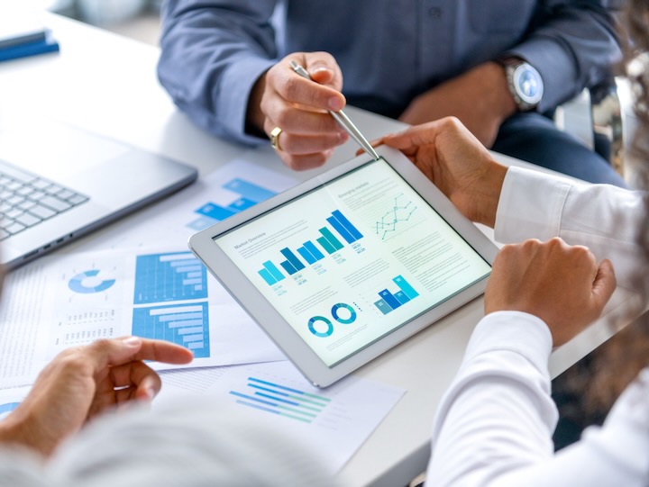 getty image of corporate hands looking at an ipad with statistics graphs on it