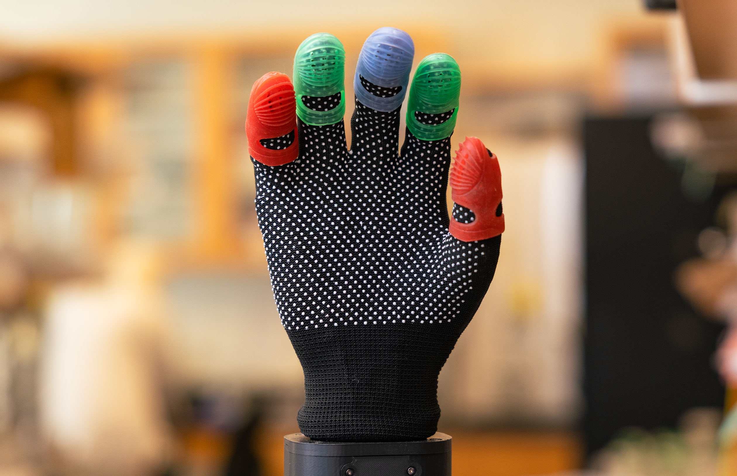 A robotic hand featuring five grippy fingertips colored in red, green and blue.