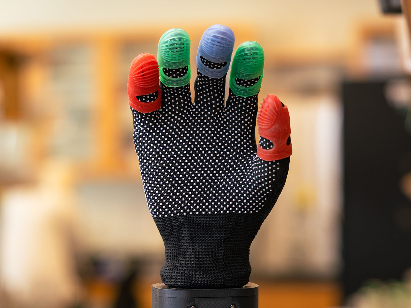 A robotic hand featuring five grippy fingertips colored in red, green and blue.
