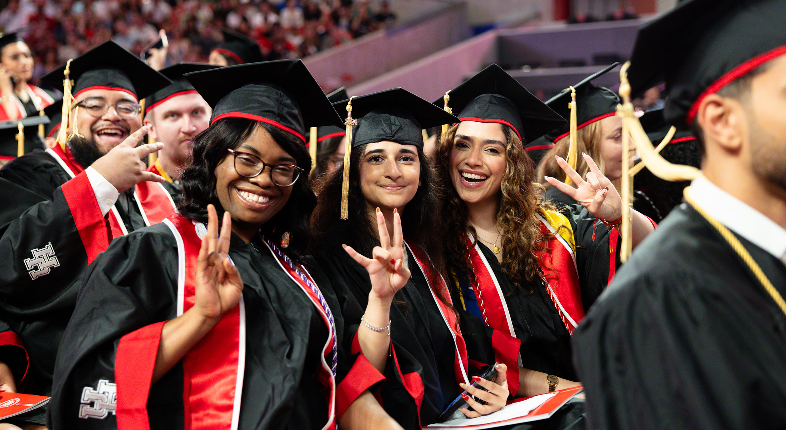 Candid photo of UH graduates smiling at graduation ceremony in Fertitta Center.