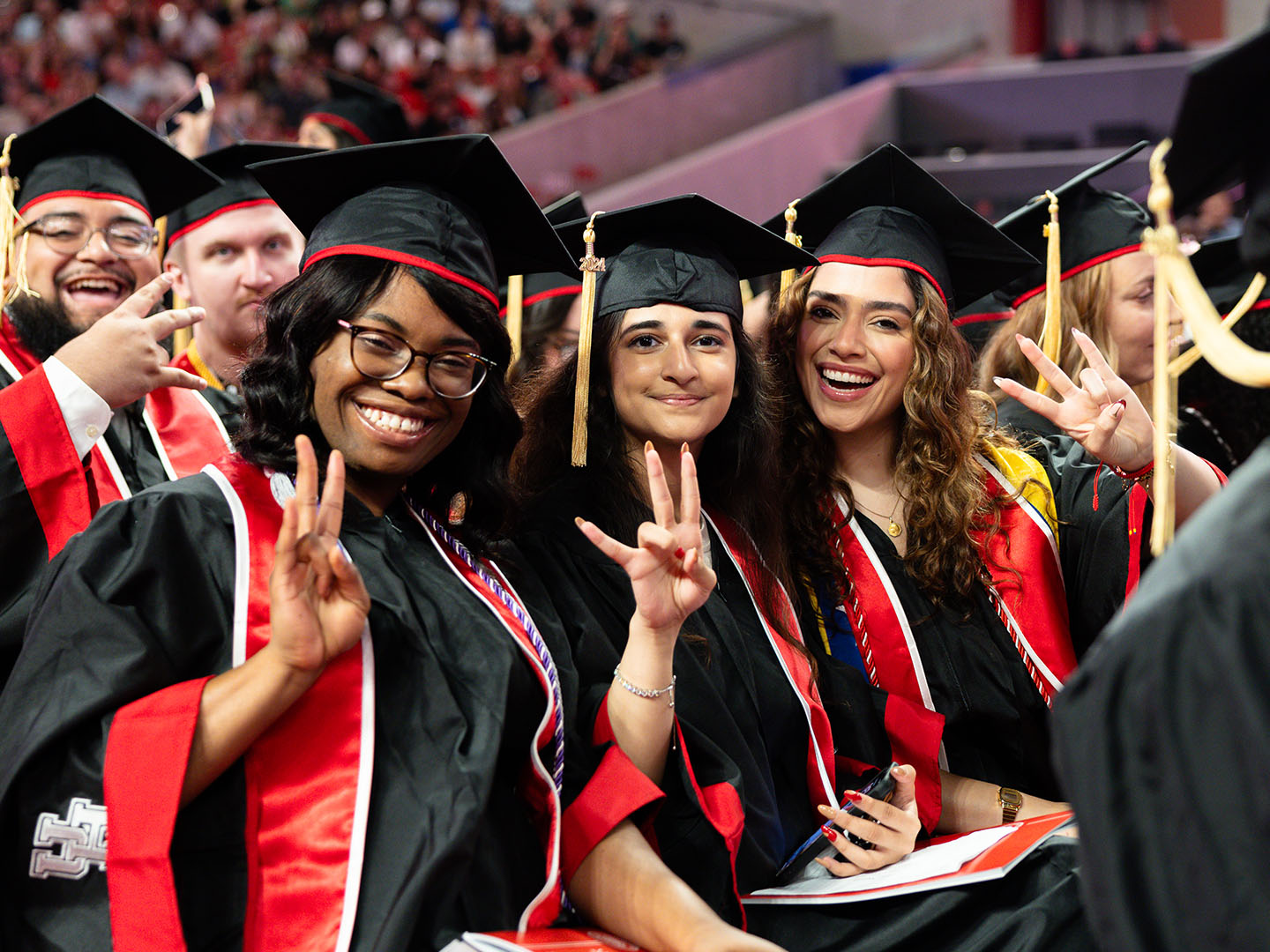 Candid photo of UH graduates smiling at graduation ceremony in Fertitta Center.