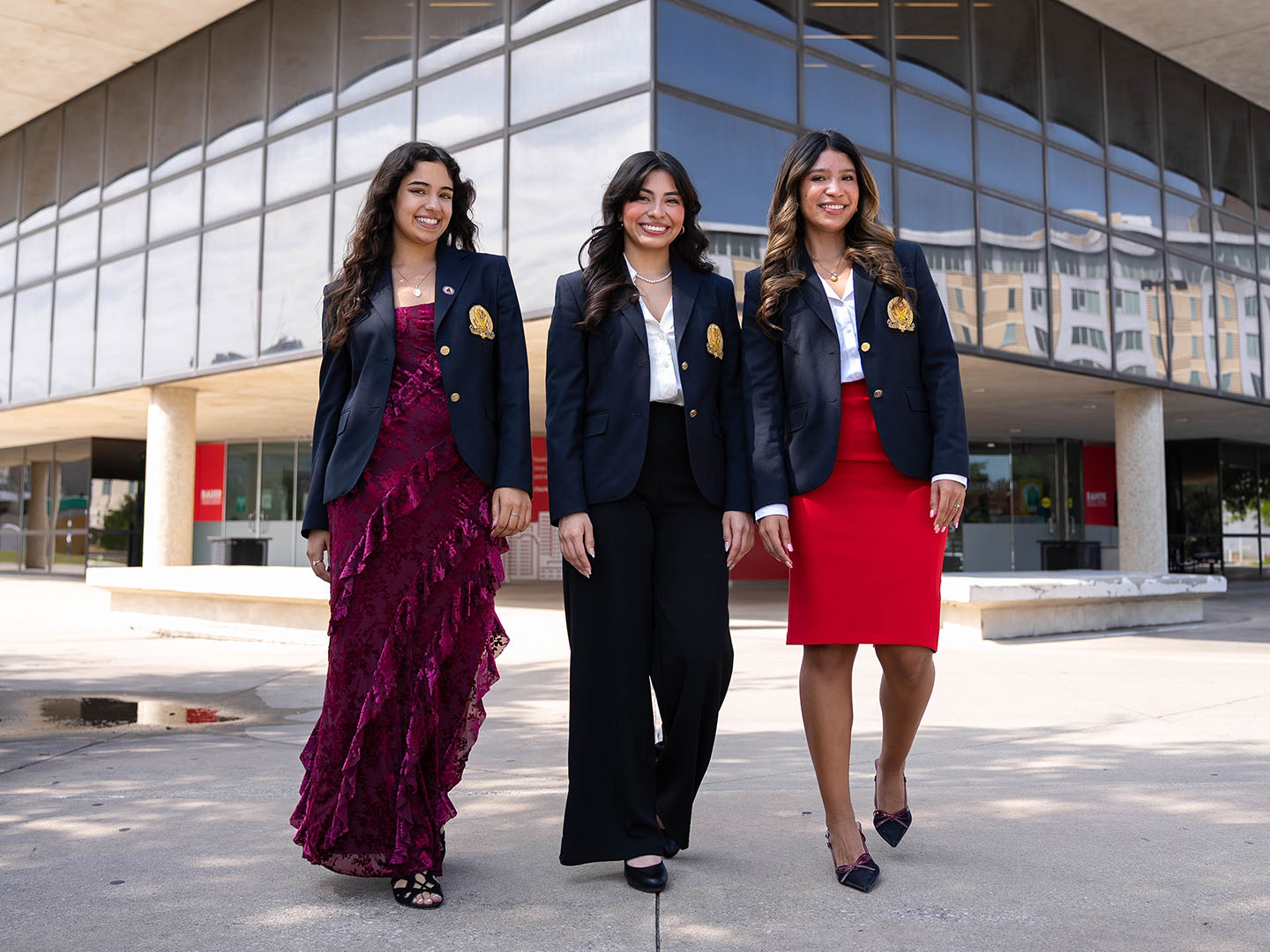 Three Wolff Center students smiling in front of Bauer College at University of Houston.