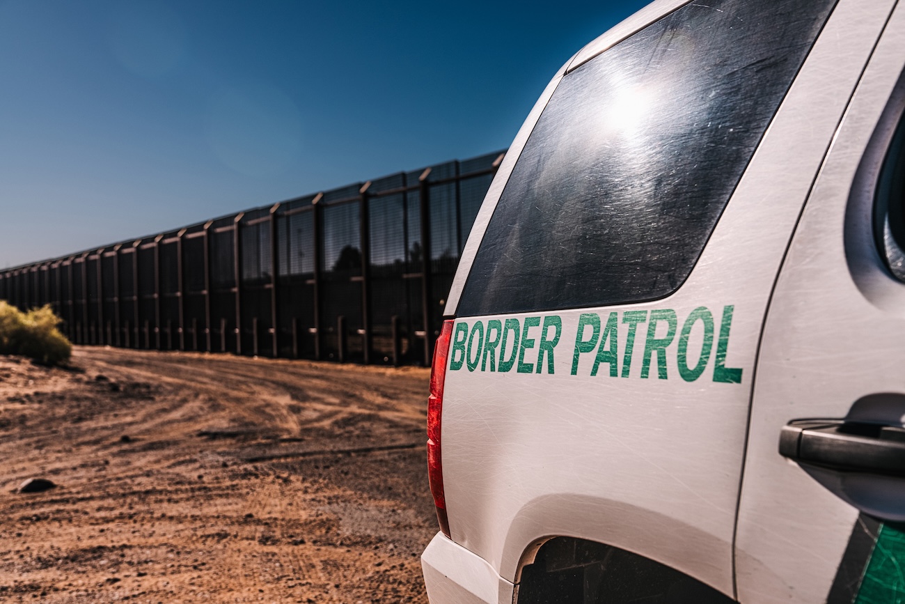 getty image of a border patrol vehicle with the border wall behind it
