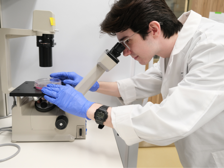 uh student cole woody works with a microscope at MD Anderson