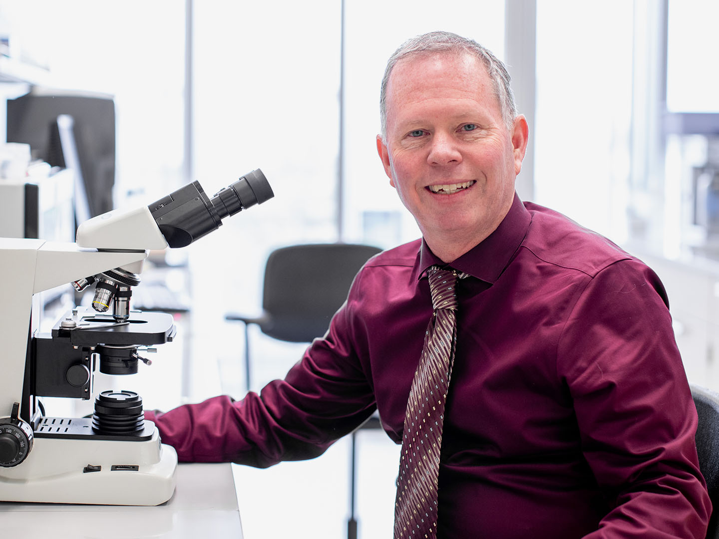 Kevin Garey sitting with a microscope.