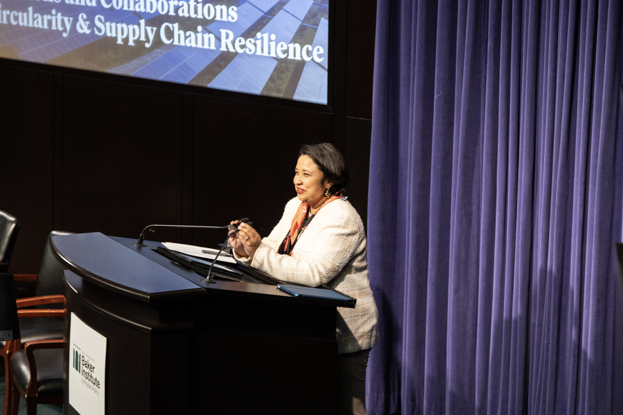 Debalina Sengupta speaking at podium with microphone.