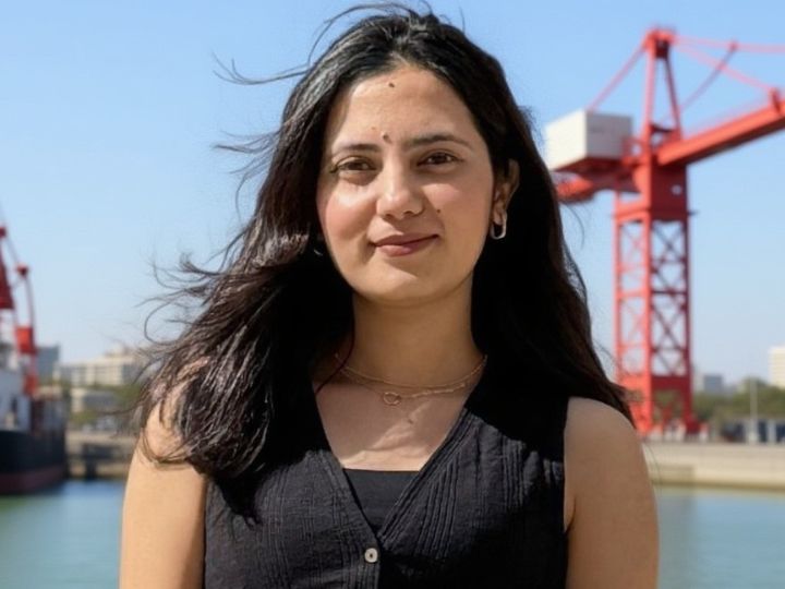 Pratikshya Tiwari Woman posing near red cranes and water.