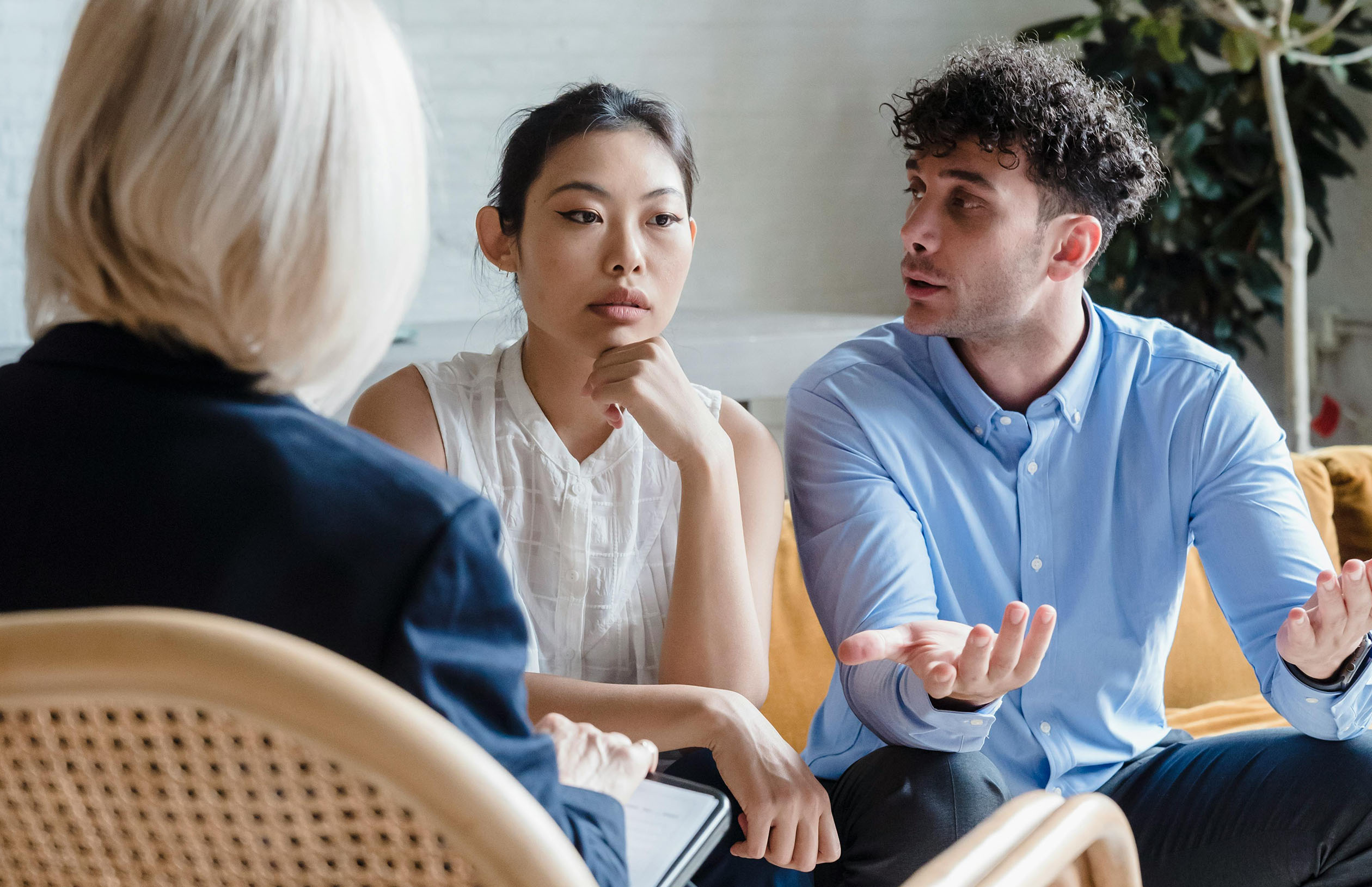 Two people sitting across from a counselor, engaged in a conversation.