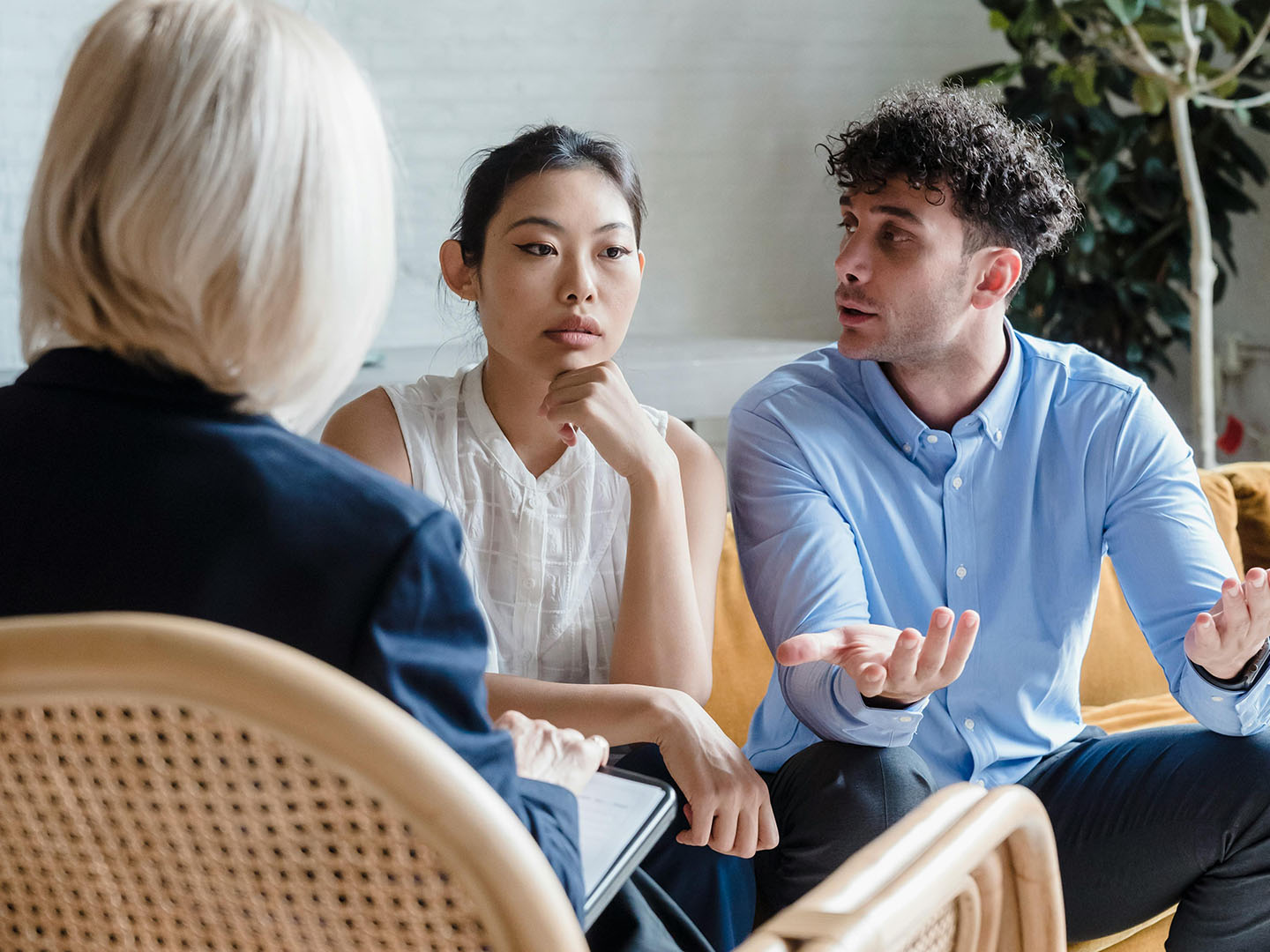 Two people sitting across from a counselor, engaged in a conversation.