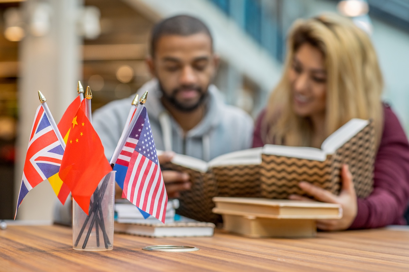 getty image of two stuents reading a textbook with international flags in a cup on the table