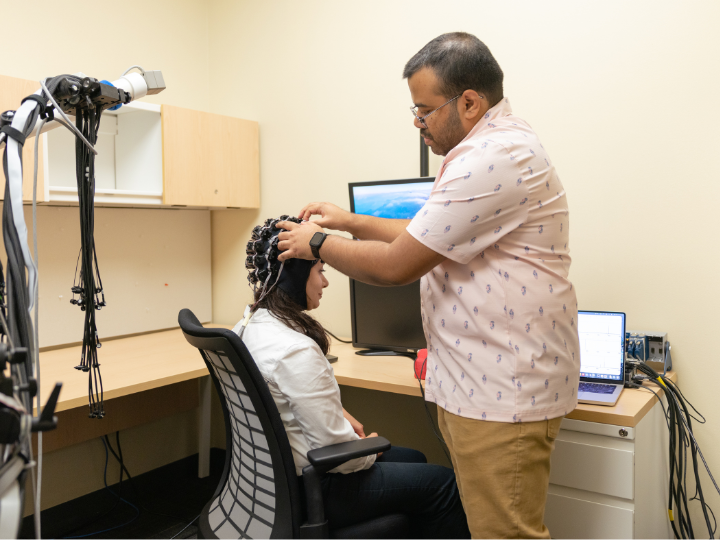 researcher adjusting brainwave monitor on study participant