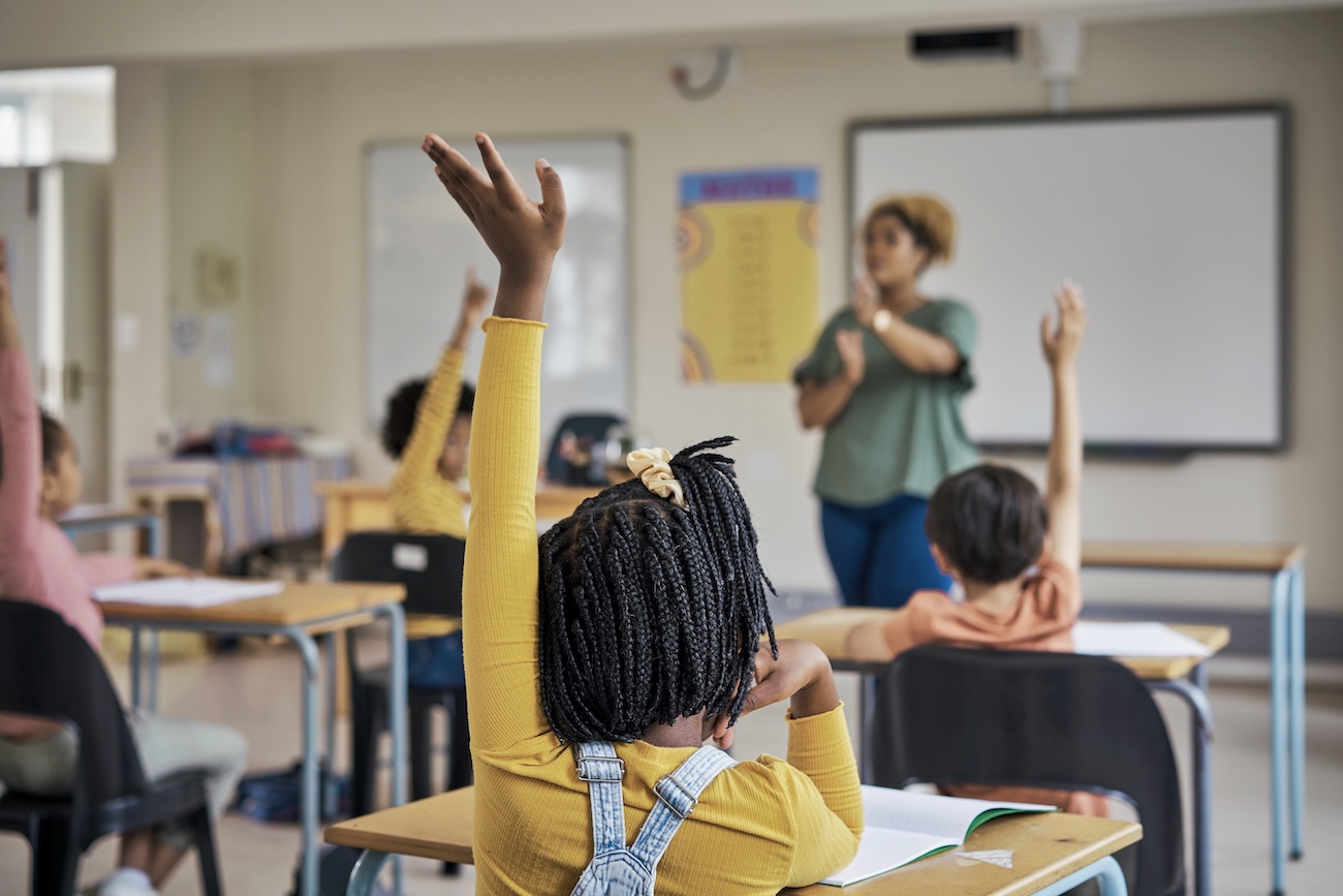 getty image of a student raising their hand in a classroom