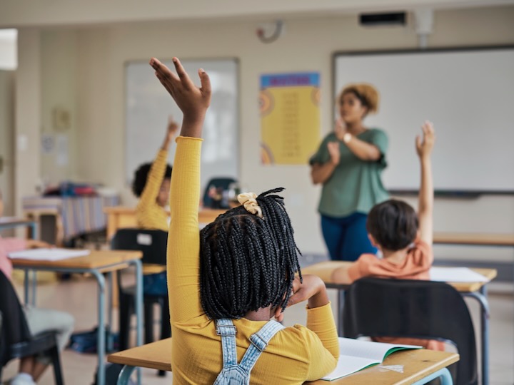 getty image of a student raising their hand in a classroom
