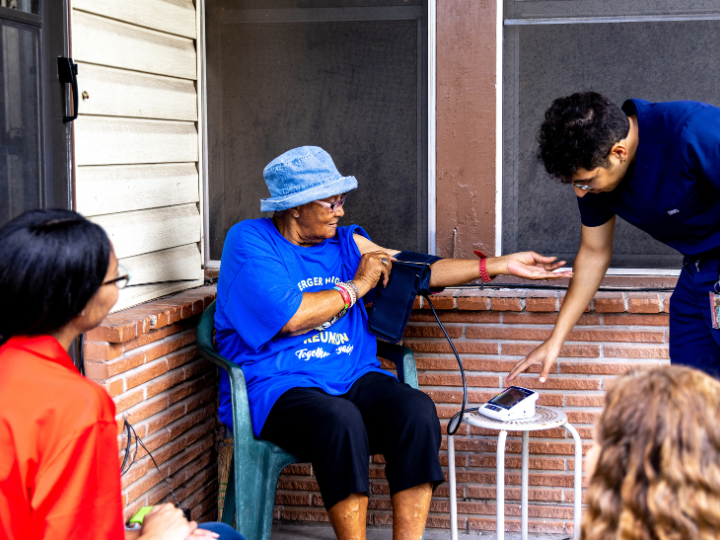 A health care worker checks an elderly woman's blood pressure on her porch.