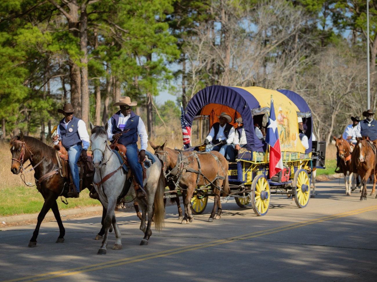 African American Riders on horseback affiliated with the Prairie View Trail Ride Association pass on a street on Go Texan Day