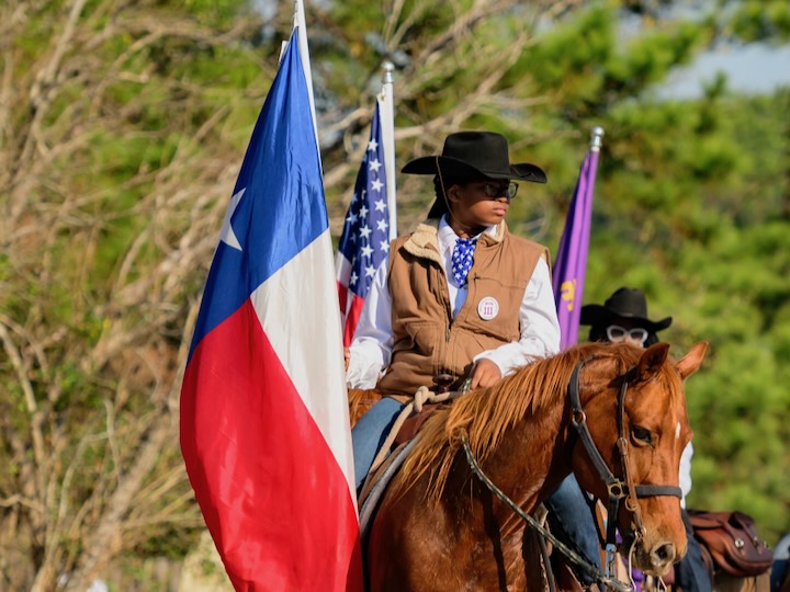 A young girl on horseback affiliated with Prairie View Trail Ride Association passes on a street on Go Texan Day