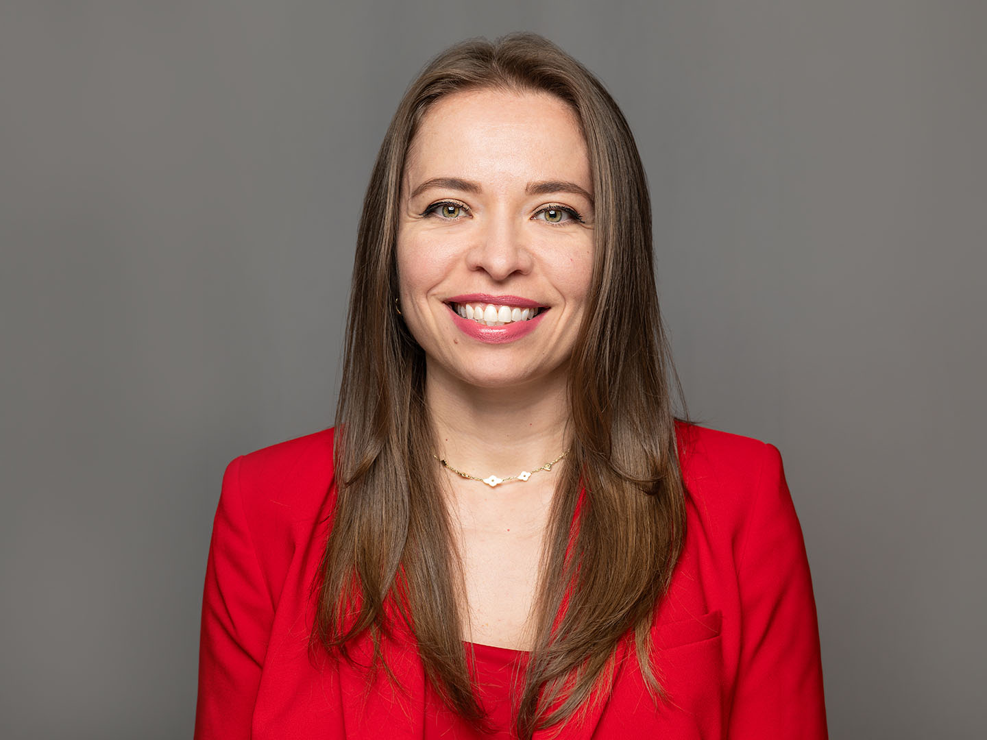 Headshot of Amanda Canales smiling, wearing a red jacket.