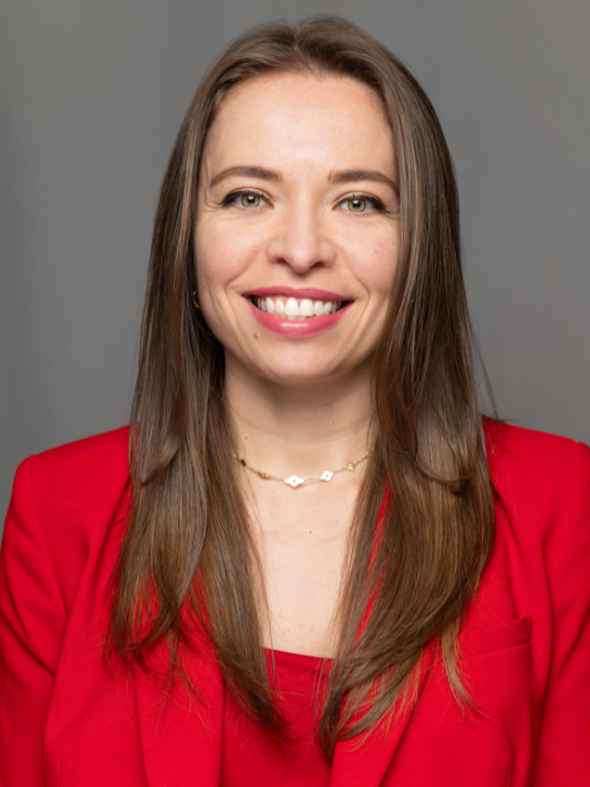 Headshot of Amanda Canales smiling, wearing a red jacket.