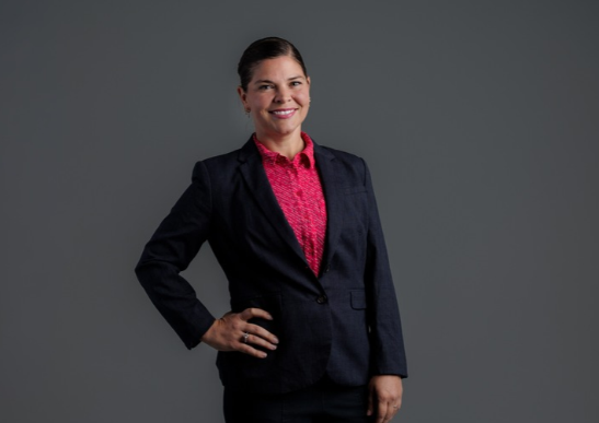 Portrait image of Marti Trummer-Cabrera smiling with her hand on her hip.