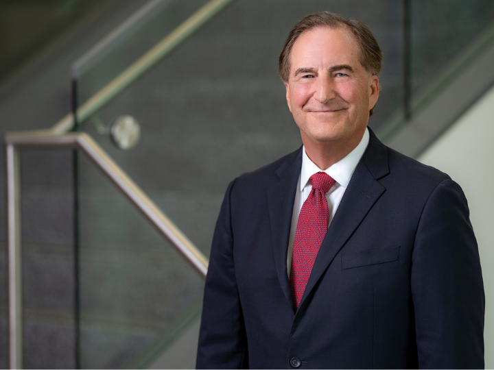 james bray wearing a navy suit with red tie