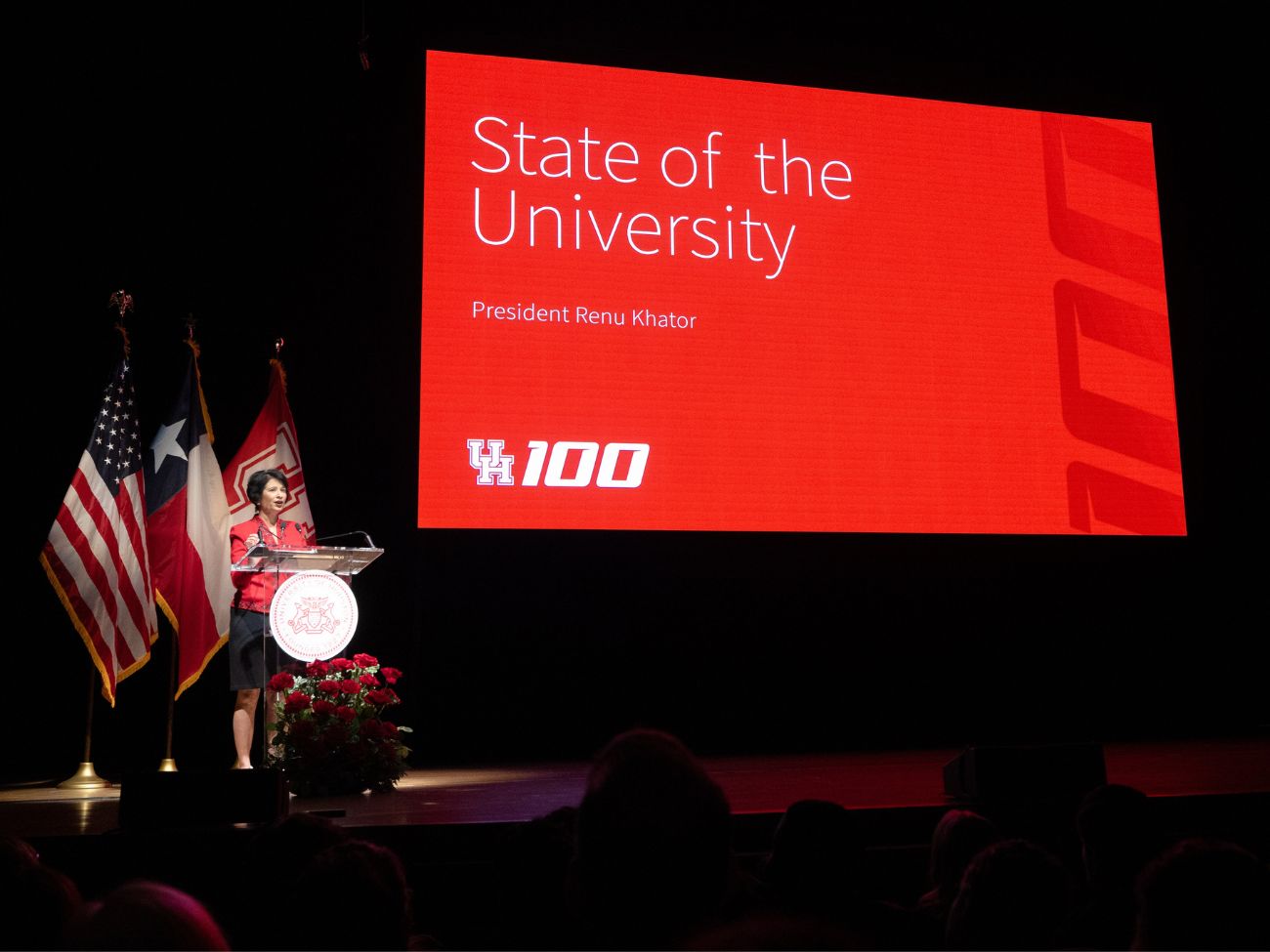 president khator speaking on stage with a display behind her that says state of the university