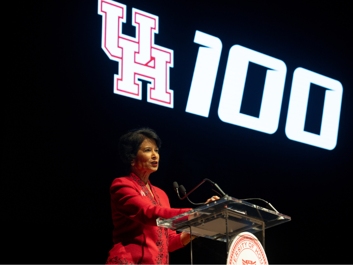 woman on stage with monitor behind her that says uh 100