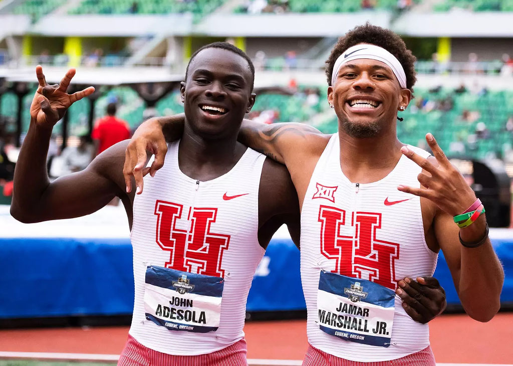 John Adesola and Jamar Marshall Jr., wearing University of Houston track uniforms, smile and gesture the Cougar hand sign after competing at the NCAA Outdoor Championships. Adesola now trains and competes unattached while completing his graduate studies.