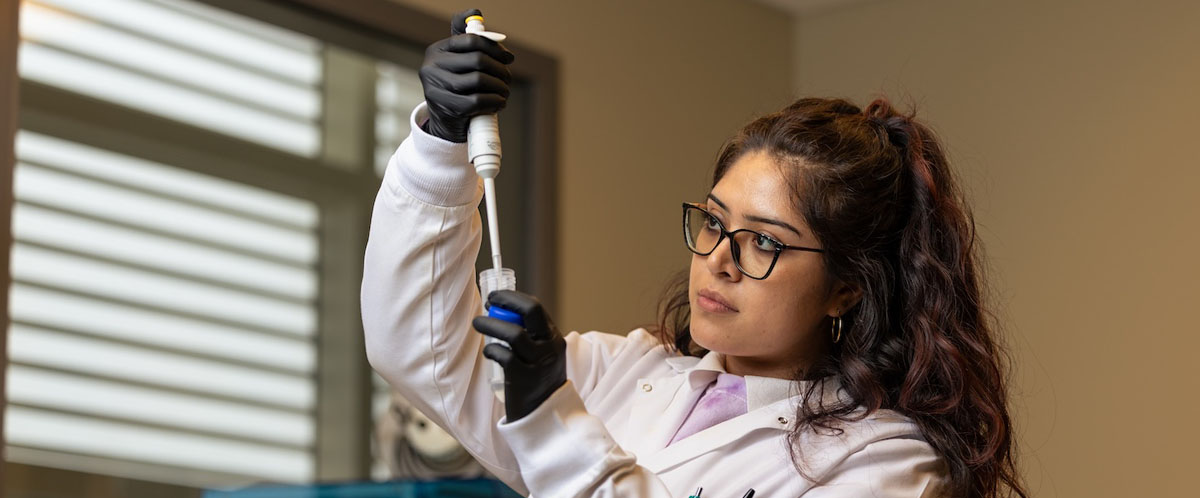 University of Houston student Ashley Guerrero uses a large pipette to place liquid into a test tube. Guerrero is part of the research team who will assist Associate Professor Dr. Weiyi Peng on her research into lupus.